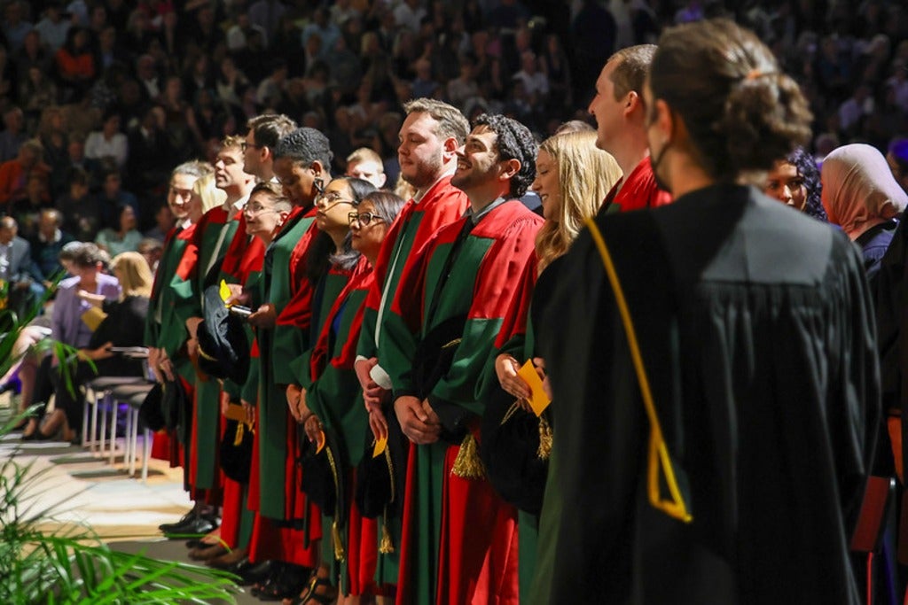 students standing while in convocation gowns