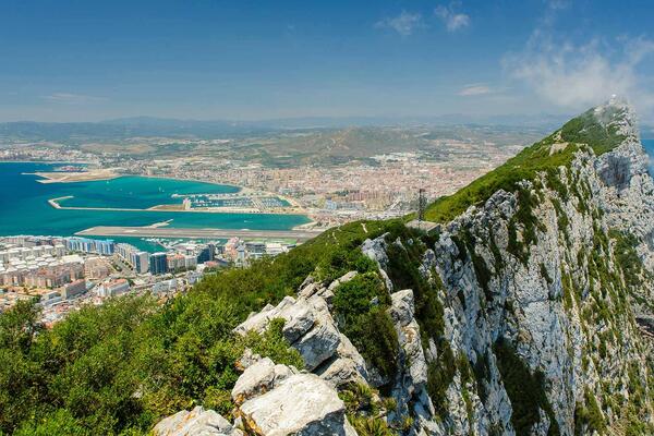 A cliff top in Gibraltar, overlooking bright blue ocean and cities