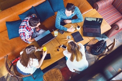 Group sitting around table with drinks and laptops